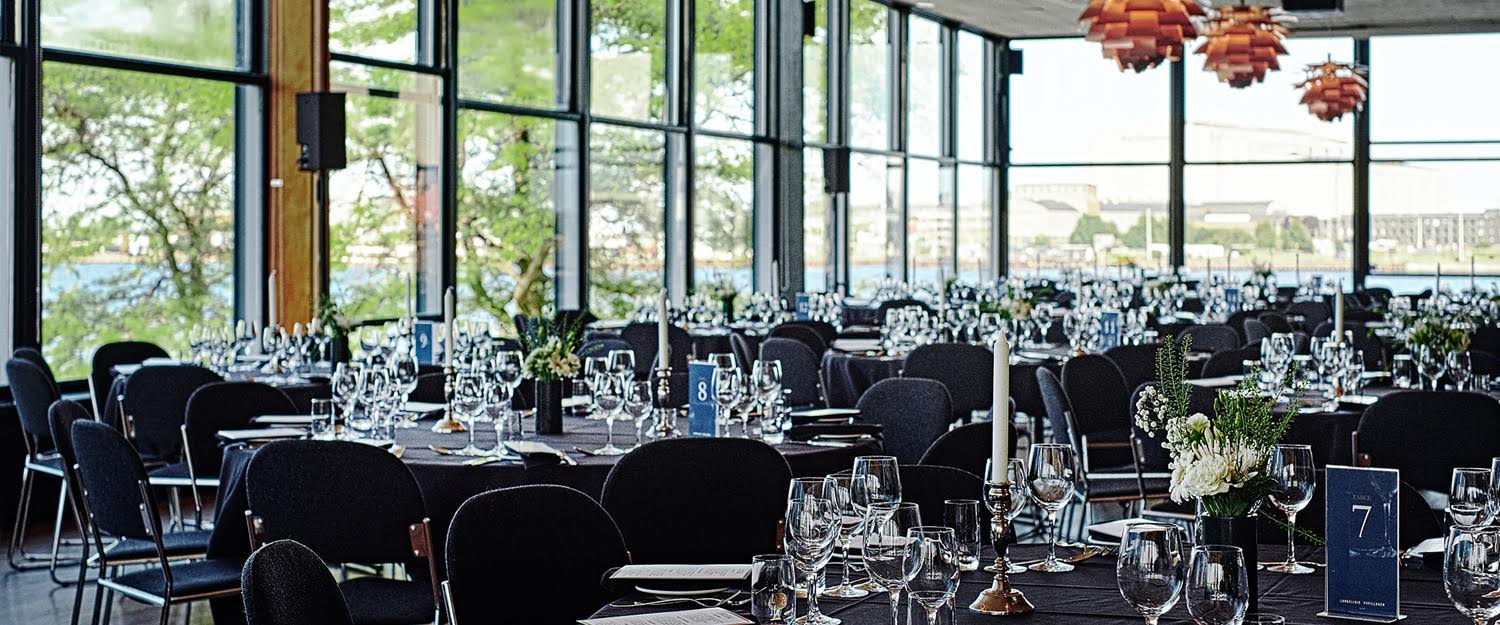 Formally set tables at event venue with a view over water